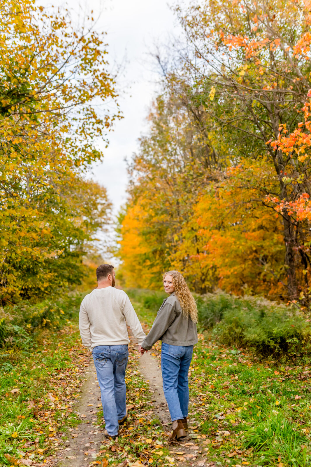 Cassie and Derrick laughing together on trail during fall engagement session